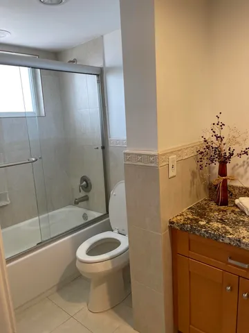 a bathroom with a granite countertop sink a toilet and shower