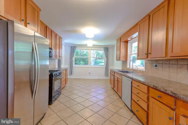 a large kitchen with stainless steel appliances granite countertop a refrigerator and a sink