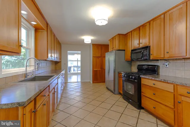 a kitchen with stainless steel appliances granite countertop a sink a stove counter space and cabinets