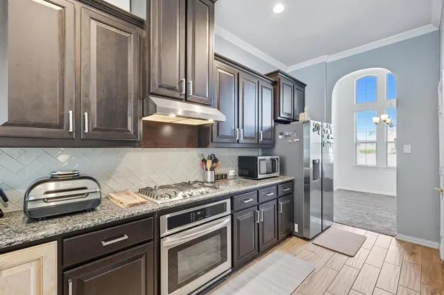 a kitchen with stainless steel appliances granite countertop a sink a stove and cabinets