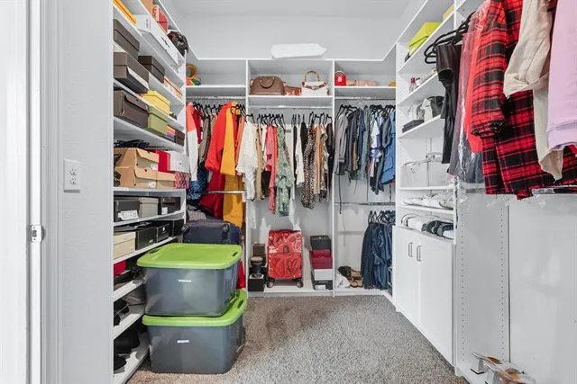 a view of walk in closet with clothes and shoes