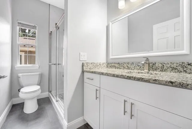 a bathroom with a granite countertop sink toilet and shower