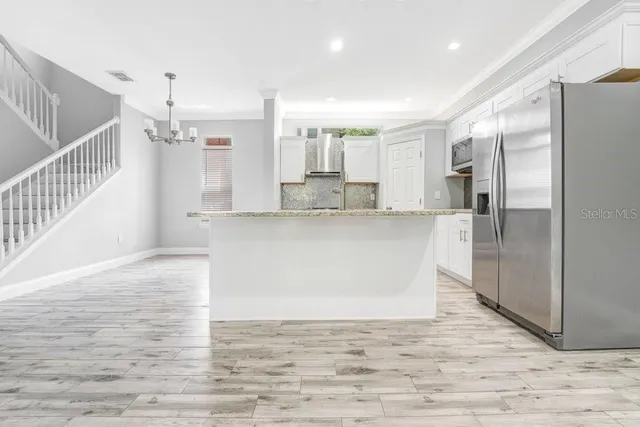 a large white kitchen with kitchen island a sink stainless steel appliances and cabinets