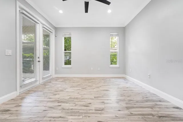 a view of an empty room with a window and wooden floor