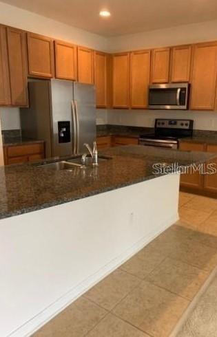 5706 Cypress Hill Road Winter Garden, FL 34787 - Photo 3 of 21 a kitchen with stainless steel appliances granite countertop a refrigerator a stove and a sink with wooden cabinets