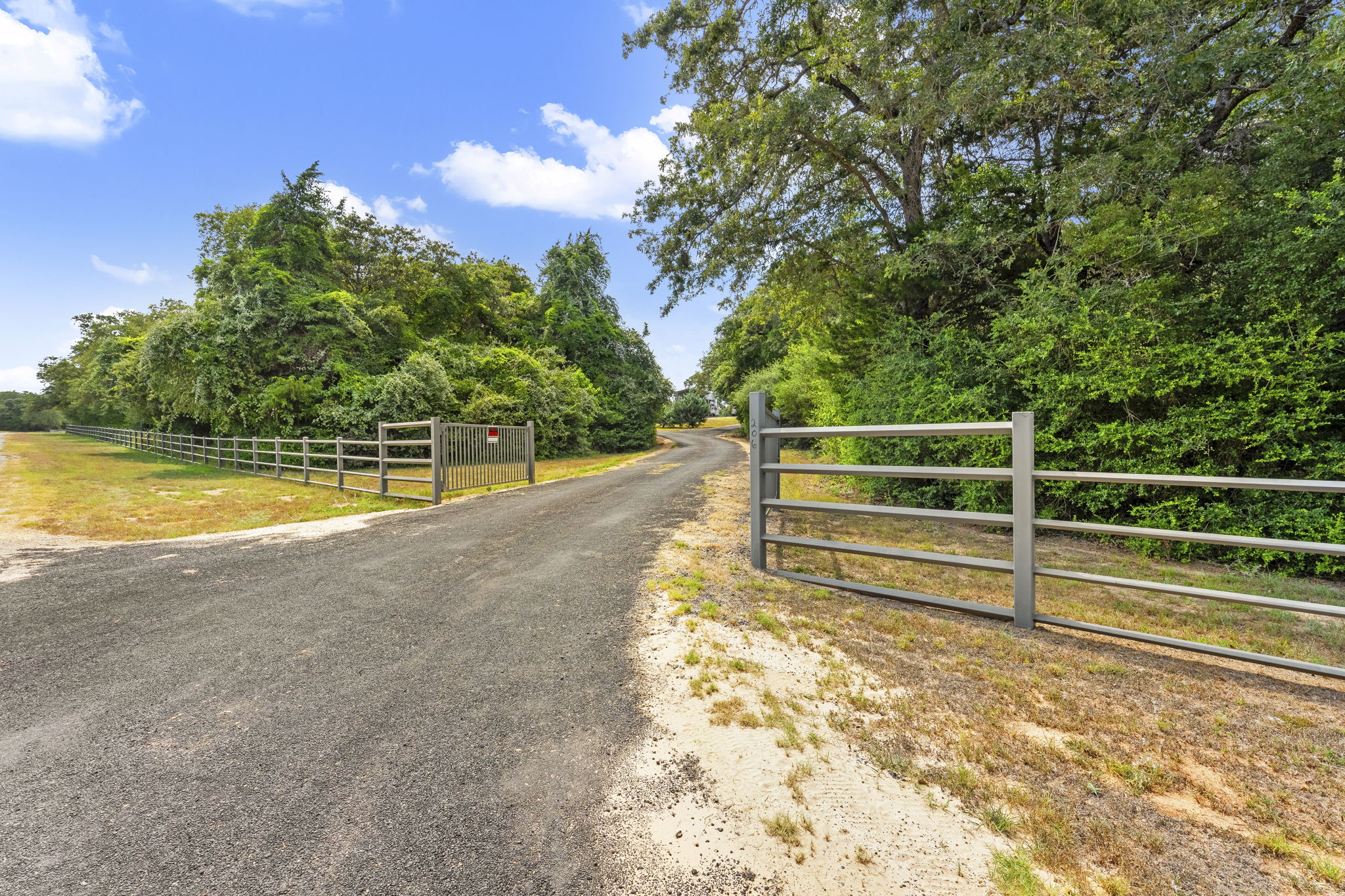 206 22 Hills Road Gause, TX 77857 - Photo 1 of 28 A secured gated entry leads down a long driveway bordered by mature trees.