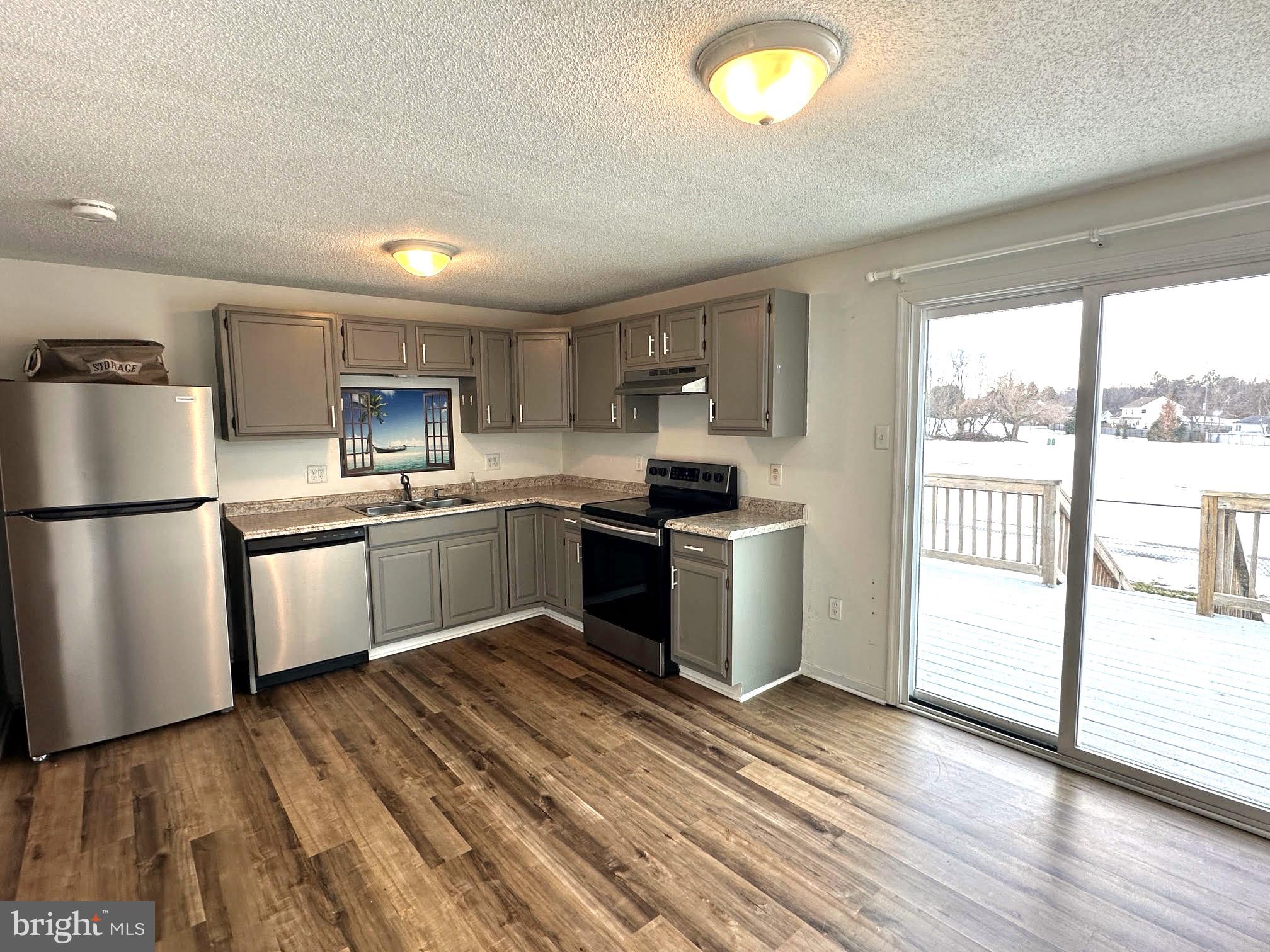 119 Cove Point Road Lusby, MD 20657 - Photo 2 of 22 a kitchen with a refrigerator a sink dishwasher with a stove and wooden floor