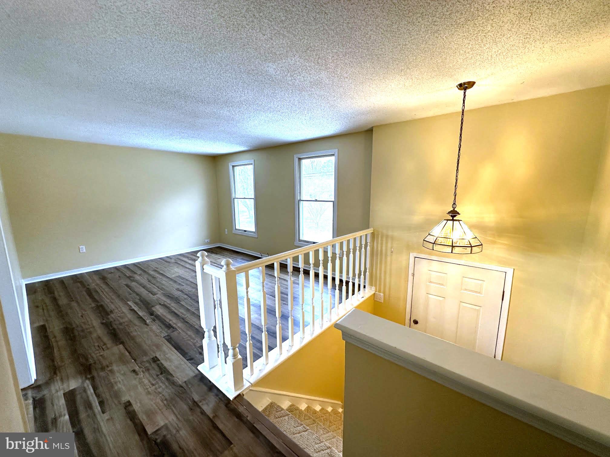 119 Cove Point Road Lusby, MD 20657 - Photo 3 of 22 a view of a hallway to an empty room with wooden floor and windows