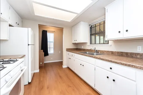 a kitchen with granite countertop a sink stove and refrigerator