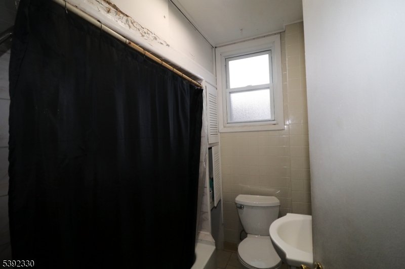 233 Adams Street Newark, NJ 07105 - Photo 3 of 14 a bathroom with a toilet a sink and a window