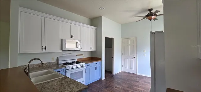 a kitchen with granite countertop white cabinets and stainless steel appliances