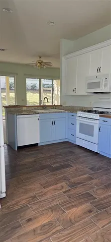 a large kitchen with granite countertop a stove and a wooden floors