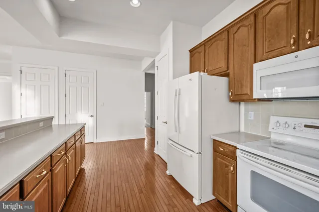 a kitchen with a refrigerator a sink and wooden floor
