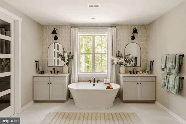 a large white kitchen with sink a window and stainless steel appliances