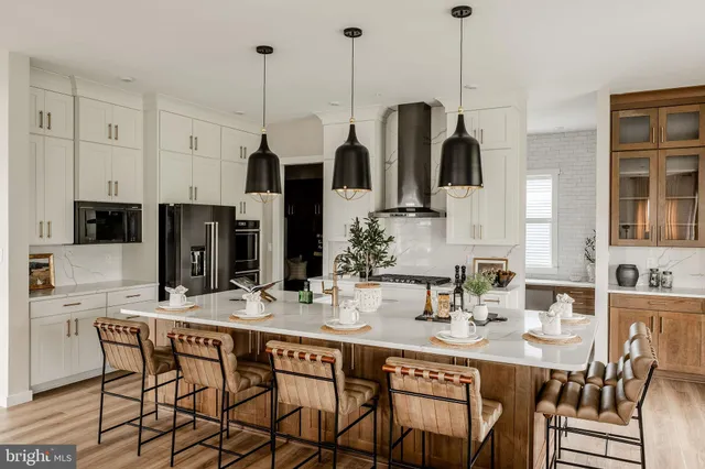 a kitchen with stainless steel appliances kitchen island granite countertop a dining table chairs and white cabinets