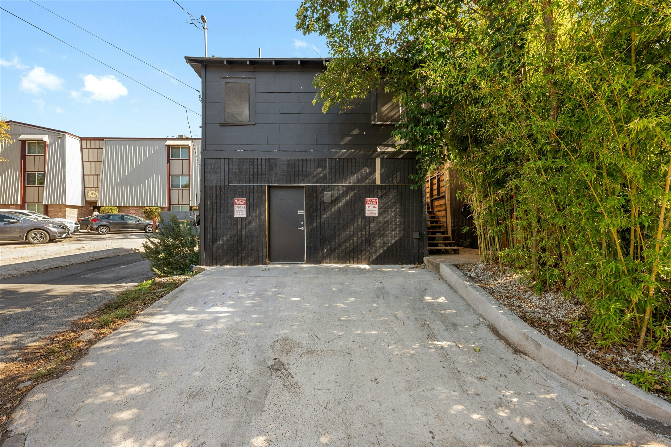 2201 Leon Street, Unit G Austin, TX 78705 - Photo 17 of 17 Concrete driveway leading to a dark-toned building with a solid exterior door and a visible window on the upper level