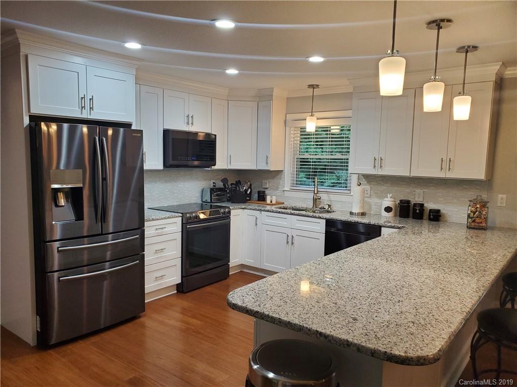 4501 Farmbrook Road Gastonia, NC 28056 - Photo 1 of 23 a kitchen with granite countertop a refrigerator a sink dishwasher a stove and white cabinets with wooden floor