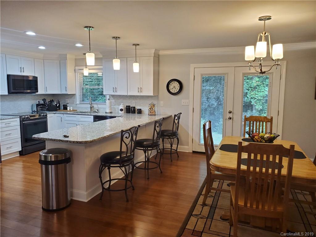 4501 Farmbrook Road Gastonia, NC 28056 - Photo 3 of 23 a kitchen with stainless steel appliances a dining table chairs stove a refrigerator and a window with wooden floors