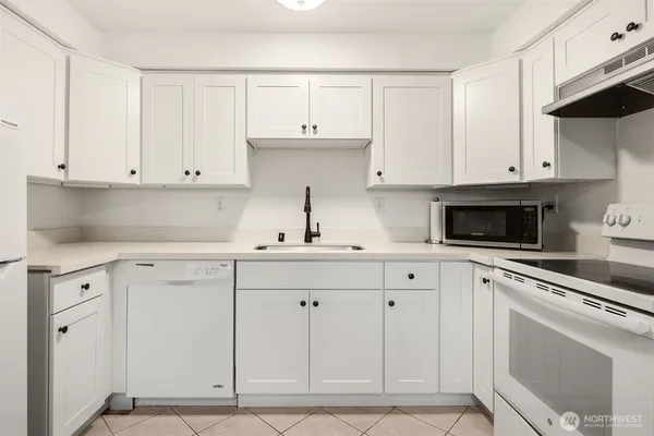 a kitchen with white cabinets and sink