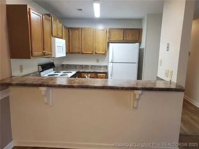 a kitchen with granite countertop a refrigerator a sink and white cabinets