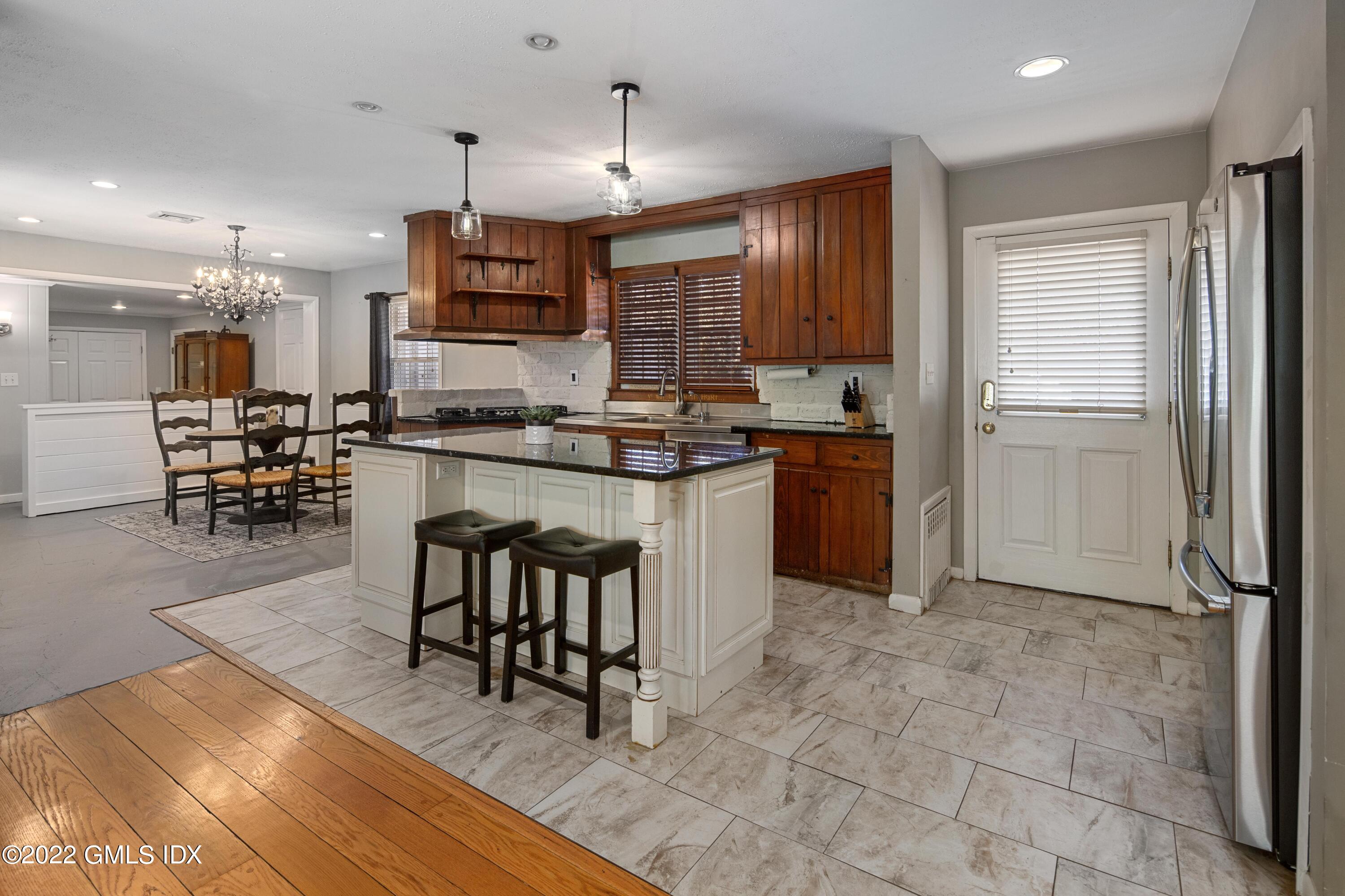 66 Simsbury Road Stamford, CT 06905 - Photo 12 of 40 a kitchen with stainless steel appliances granite countertop a stove top oven a sink dishwasher a dining table and chairs with wooden floor