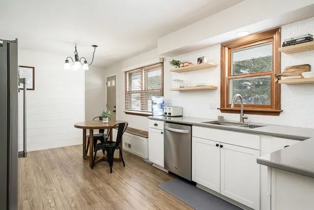 a kitchen with stainless steel appliances granite countertop white cabinets a table and chairs
