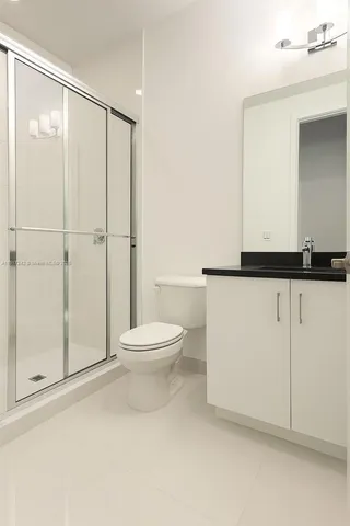 a bathroom with a granite countertop sink toilet and shower