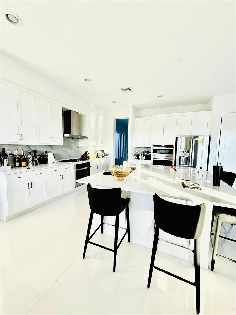 8185 Crystal Downs Avenue Boca Raton, FL 33434 - Photo 8 of 27 a kitchen with stainless steel appliances kitchen island a white table chairs and a refrigerator