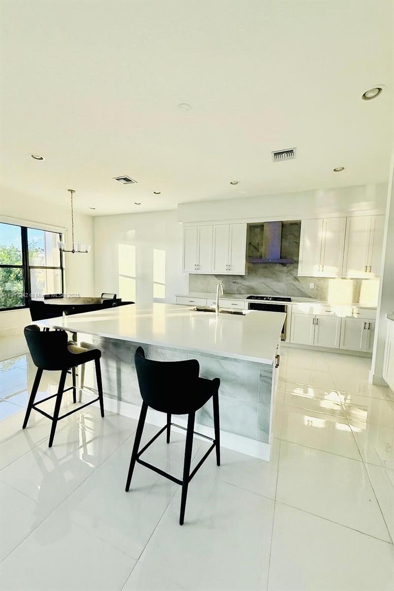 8185 Crystal Downs Avenue Boca Raton, FL 33434 - Photo 9 of 27 a living room with stainless steel appliances kitchen island granite countertop a table chairs microwave and sink