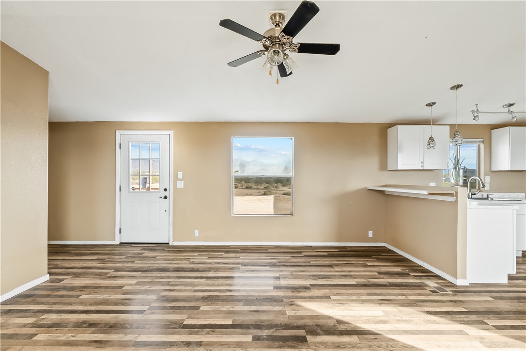 3649 Araby Road Golden Valley, AZ 86413 - Photo 11 of 29 Open-concept living area featuring wood-finish flooring, a ceiling fan with integrated lighting, and a white paneled door with windowpanes