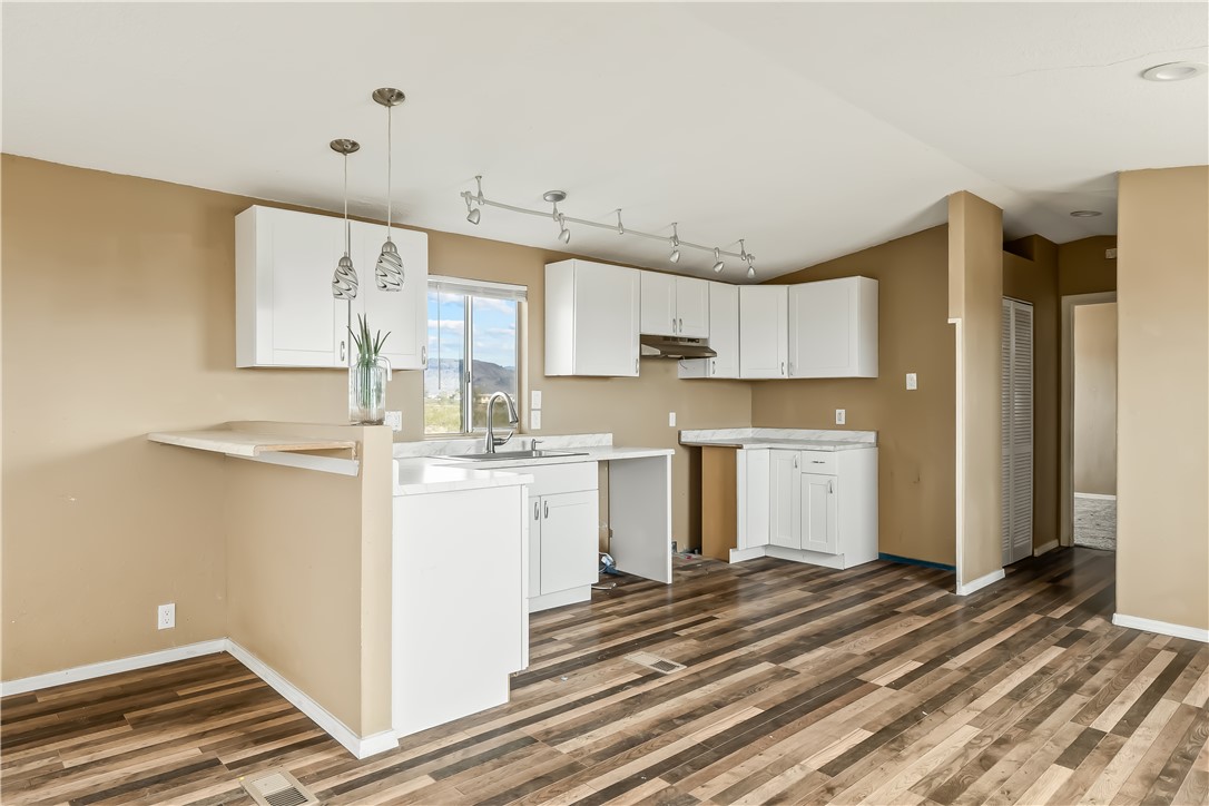 3649 Araby Road Golden Valley, AZ 86413 - Photo 14 of 29 Open-concept kitchen featuring wood-finish flooring, white cabinetry, light-toned countertops, and track lighting