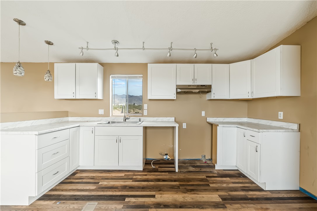 3649 Araby Road Golden Valley, AZ 86413 - Photo 15 of 29 Kitchen featuring white cabinetry with silver-tone hardware, wood-finish flooring, and light-toned countertops