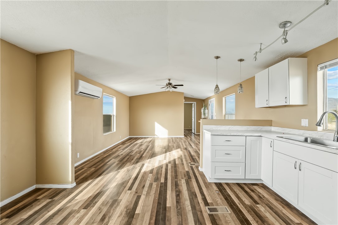 3649 Araby Road Golden Valley, AZ 86413 - Photo 16 of 29 Open-concept living space featuring wood-finish flooring, a kitchen island with white cabinetry and a sink, pendant lighting, track lighting, and a ceiling fan