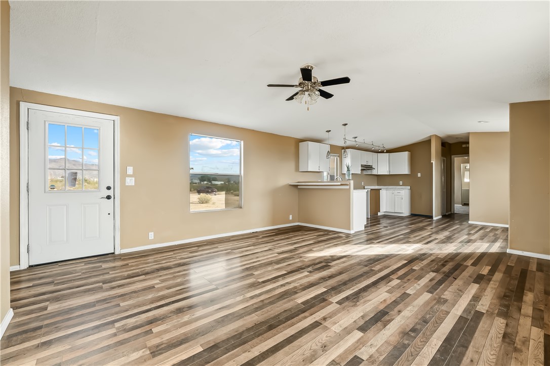 3649 Araby Road Golden Valley, AZ 86413 - Photo 10 of 29 Open-concept living space featuring wood-finish flooring, a contemporary ceiling fan, and a kitchen area with white cabinetry and pendant lighting