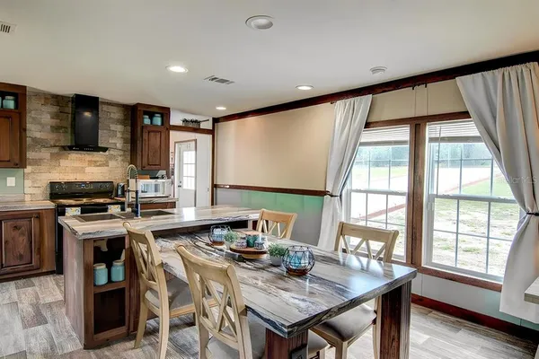 a open kitchen with stainless steel appliances granite countertop a stove a refrigerator a sink dishwasher a dining table and chairs with wooden floor