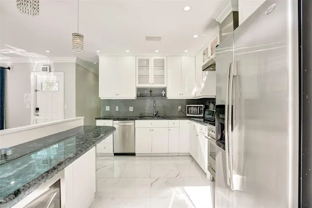 a large kitchen with stainless steel appliances granite countertop a refrigerator and a sink
