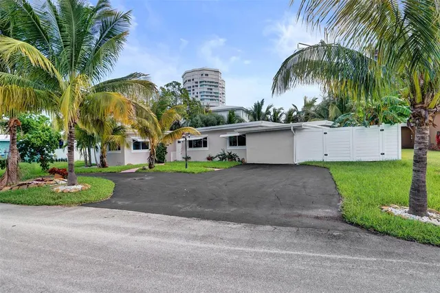 a view of a white house with a yard and palm trees