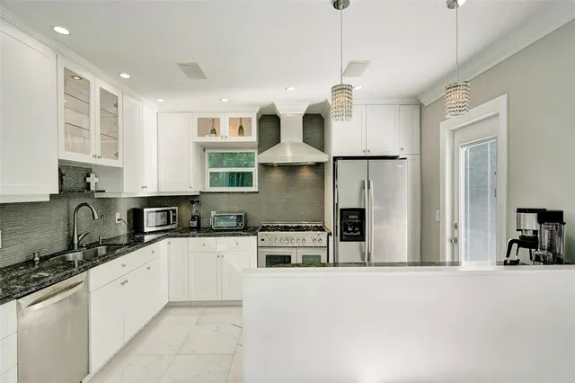 a kitchen with stainless steel appliances granite countertop a refrigerator a stove a sink and white cabinets