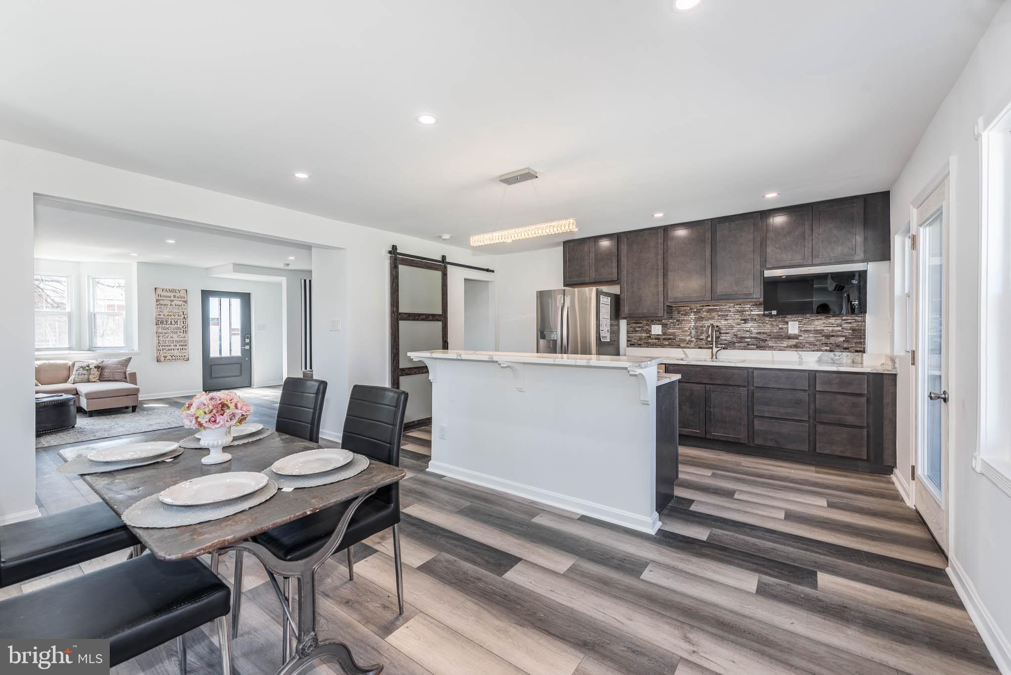 1510 Northbourne Road Baltimore, MD 21239 - Photo 8 of 32 a kitchen with a table chairs a stove a microwave and cabinets