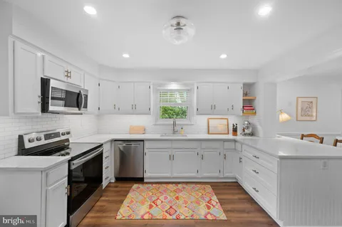 a large kitchen with stainless steel appliances granite countertop a sink and dishwasher a stove top oven with white countertops