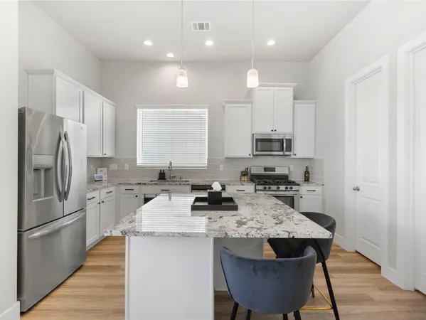 a kitchen with stainless steel appliances granite countertop a sink stove refrigerator and cabinets