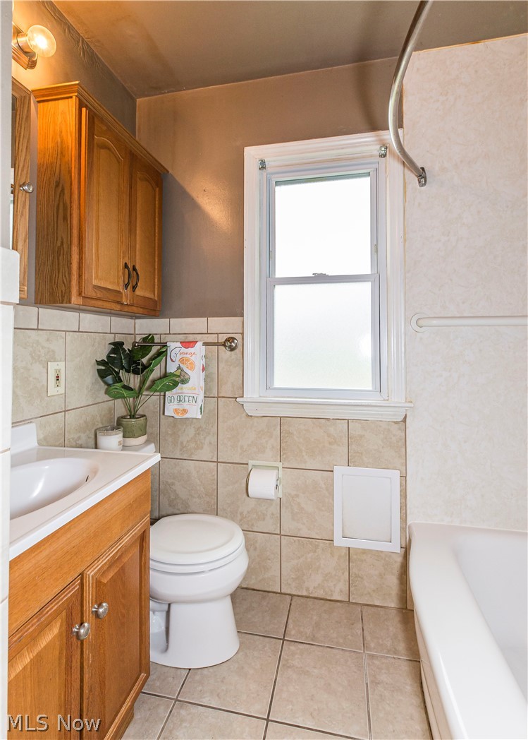 6203 Snow Road Parma, OH 44129 - Photo 16 of 29 Bathroom featuring tile walls, backsplash, toilet, tile floors, and vanity