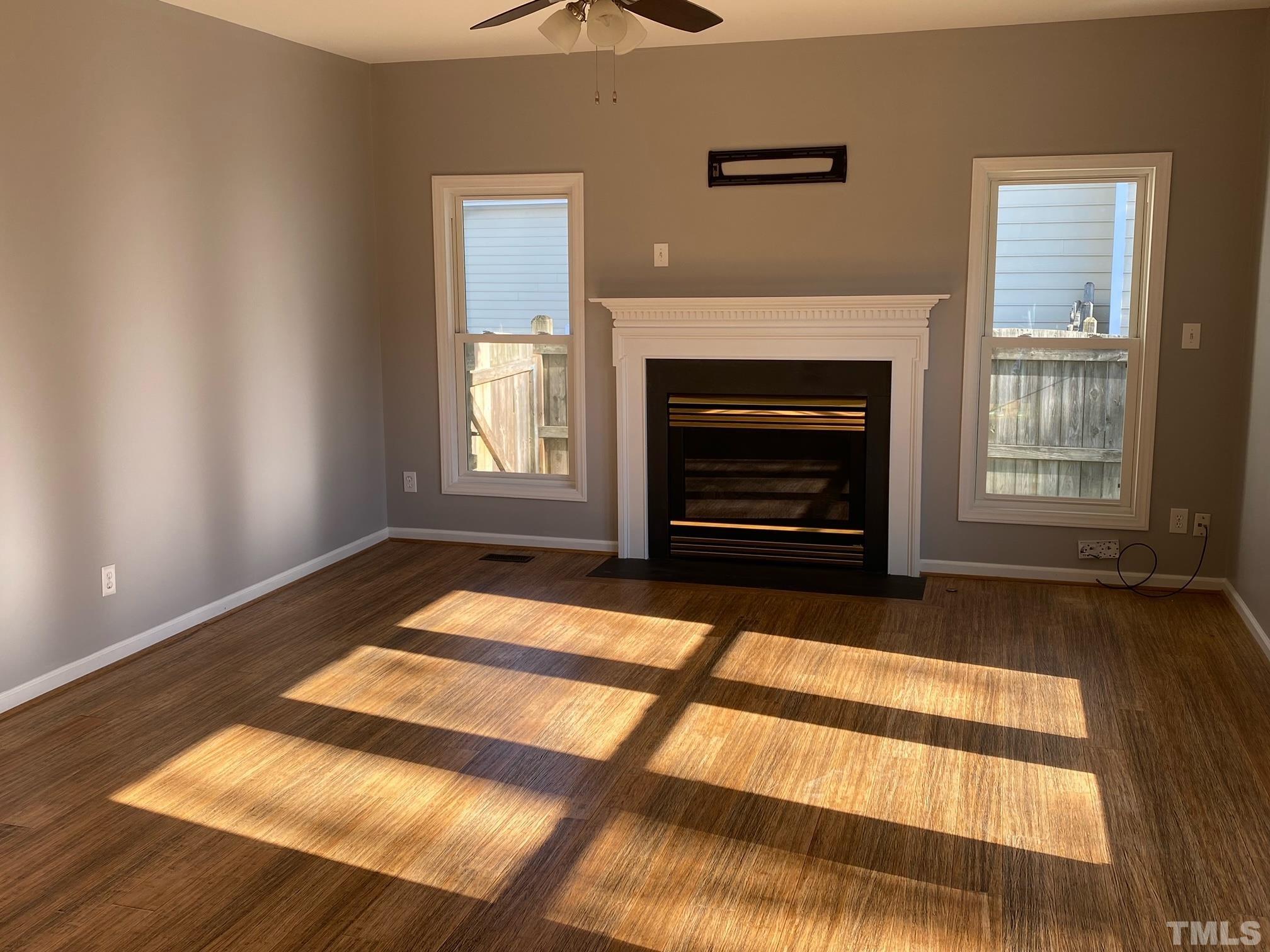 9821 Rockledge Drive Raleigh, NC 27617 - Photo 11 of 26 a view of an empty room with wooden floor fireplace and a window