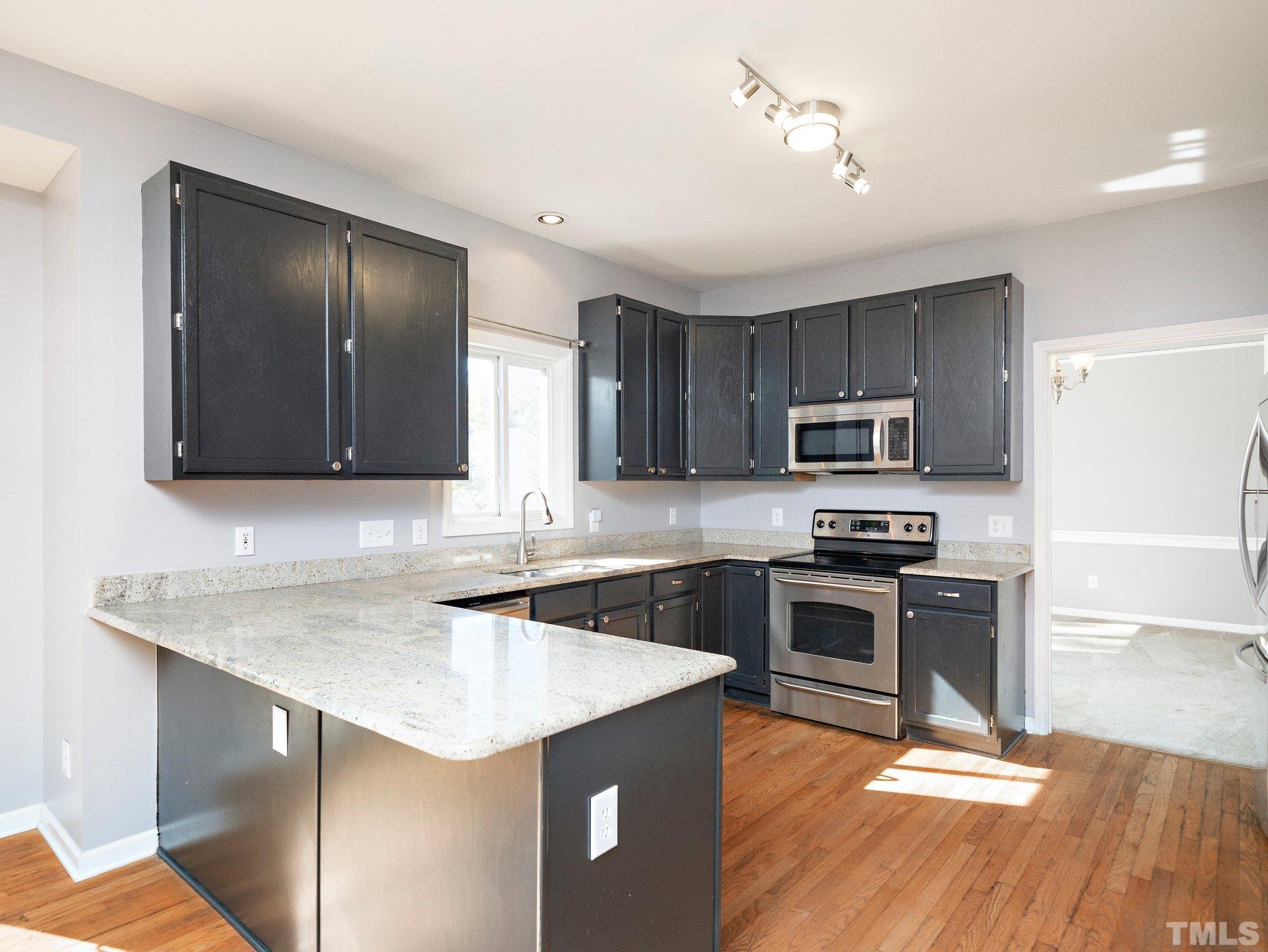 9821 Rockledge Drive Raleigh, NC 27617 - Photo 10 of 26 a kitchen with stainless steel appliances granite countertop a sink stove microwave and refrigerator