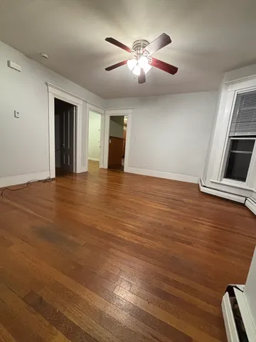 a view of an empty room with window and wooden floor
