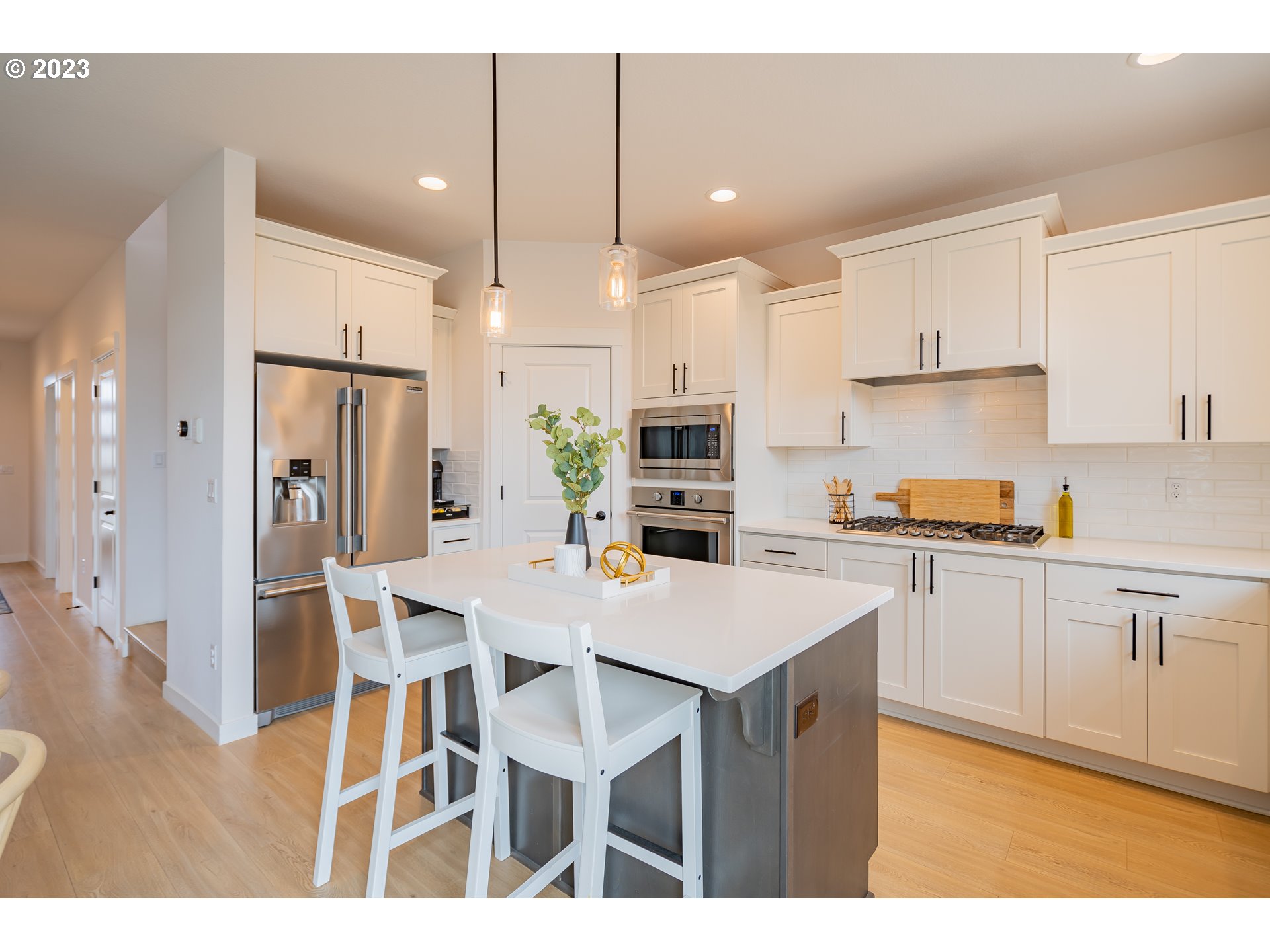 8719 North 1st Street Ridgefield, WA 98642 - Photo 13 of 45 a kitchen with stainless steel appliances granite countertop a refrigerator a sink dishwasher a stove a dining table and chairs with wooden floor