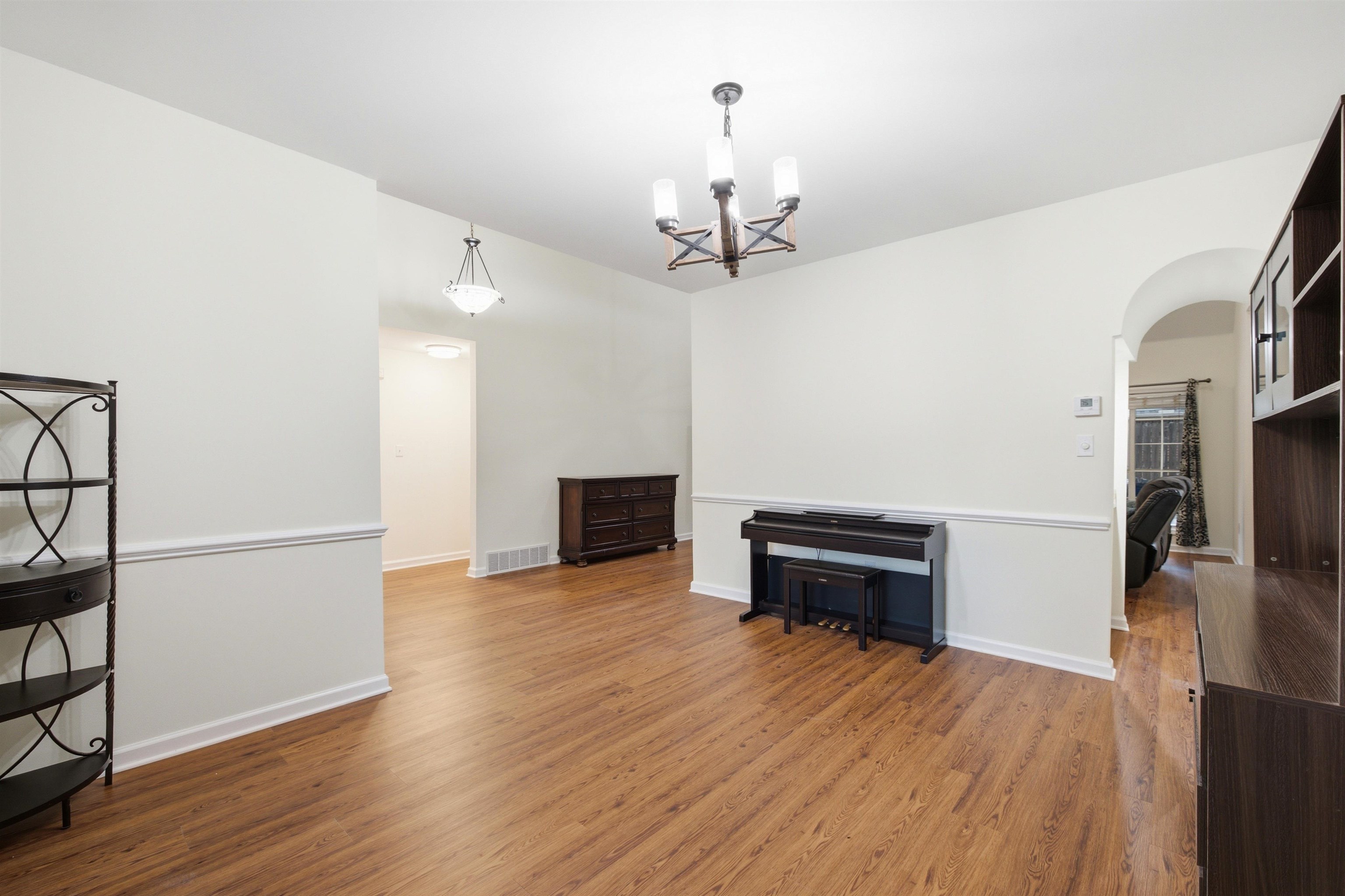 96 Berryfield Cove Collierville, TN 38017 - Photo 7 of 39 Living area featuring wood-finish flooring, white walls with chair rail molding, and a chandelier with a dark bronze finish