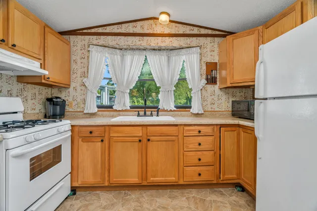 a kitchen with stainless steel appliances granite countertop a refrigerator a sink dishwasher and white cabinets with wooden floor