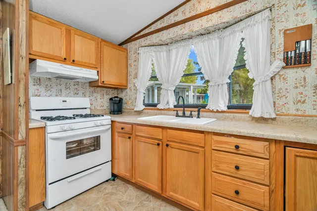 a kitchen with stainless steel appliances granite countertop a stove a sink and a microwave oven