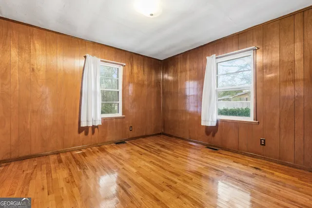 a view of empty room with wooden floor and windows